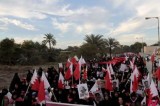 Bahraini anti-gov’t protesters take to a street waving images of those jailed or dead