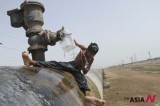 An Indian boy bathes from leaking pipe in water-deficient Gujarat state