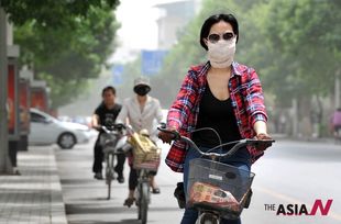 A Chinese woman covers her face to protect from floating dust