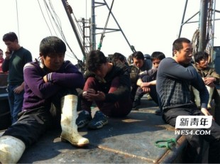 Released Chinese fishermen sitting in the boat on the port of Dalian after 13 days of torment