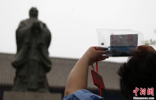 A parent praying in front of the statue of Confucius in Beijing