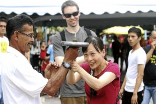 Cheong trying to hold a spinning top at the Uri top demonstration with her friend Oksanen from Finland, standing behind