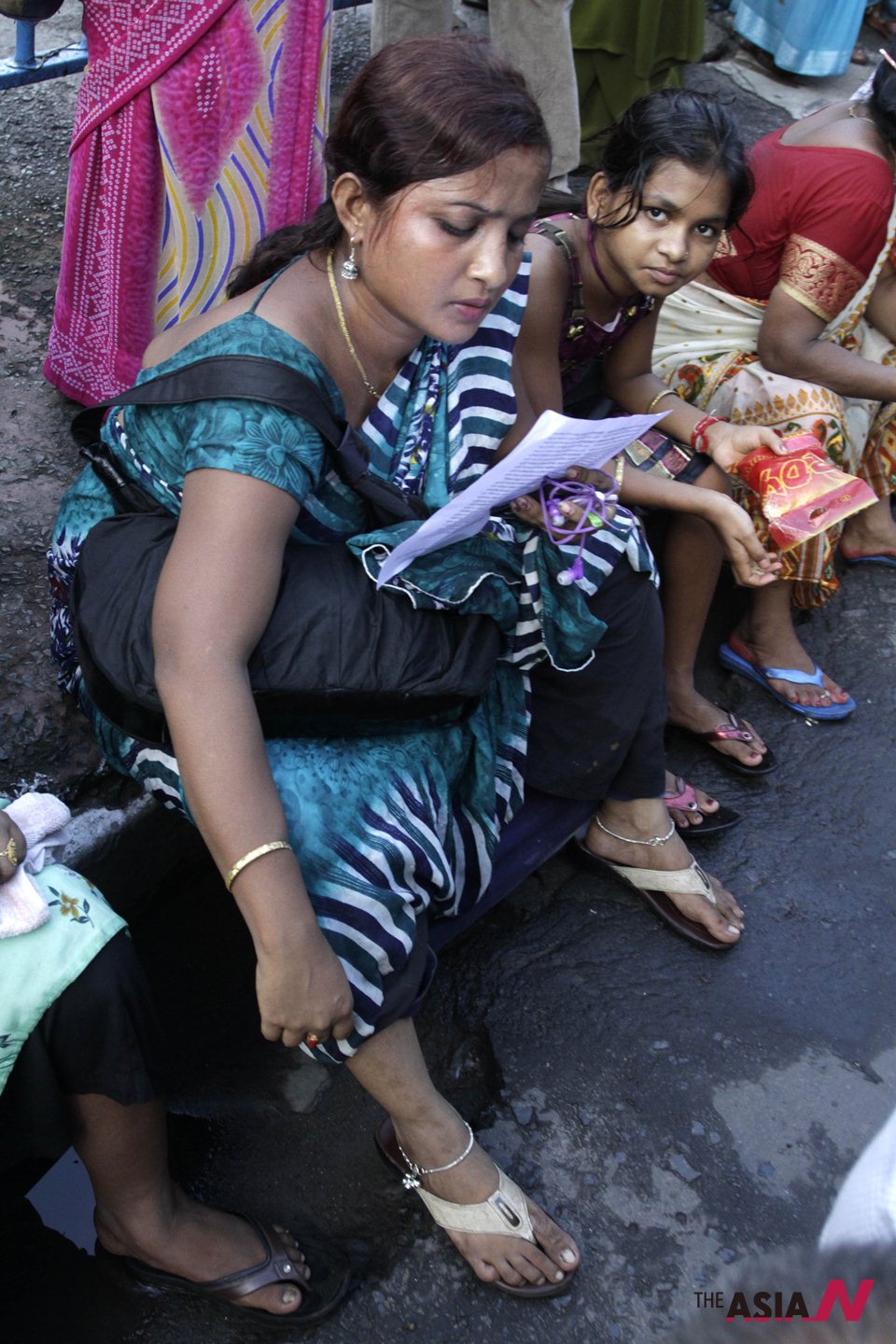 An Indian sex worker reads a leaflet as she sit beside a pavement during a ...