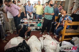 (130815) -- CAIRO, Aug. 15, 2013 (Xinhua) -- Egyptians stand beside dead bodies at a mosque where lines of bodies wrapped in shrouds were laid out in Cairo, Egypt, Aug. 15, 2013. At least 525 people were killed and 3,717 others injured across Egypt in clashes between supporters of ousted President Mohamed Morsi and the security troops, after the latter dispersed Wednesday two major pro-Morsi sit-ins in Cairo and Giza, a Health Ministry official said Thursday.  (Photo : Xinhua/Li Muzi)