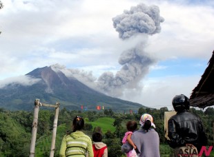 Villagers watch as Mount Sinabung sinabung spews volcanic material in Karo, North Sumatra, Indonesia, Sunday, Nov. 24, 2013. Officials raised the alert status of Sinabung to the highest level after a series of overnight eruptions. (AP/NEWSis)