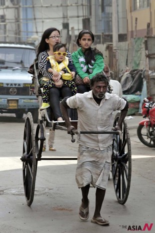 Two women and a child ride on a hand pulled rickshaw in Kolkata, India, Jan. 31, 2014. Though most cities offer auto rickshaw services, Kolkata is the only Indian city where hand-pulled rickshaws still exist. Human-powered rickshaws have been discouraged or outlawed in many countries due to concern for the welfare of rickshaw workers. (Photo : AP/NEWSis)