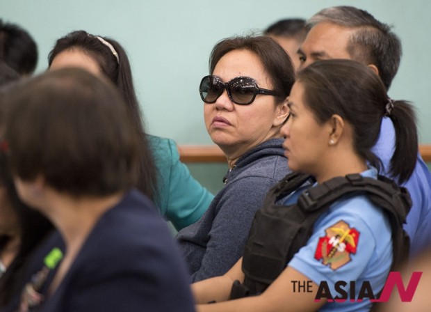 Janet Lim Napoles, center in sunglasses, a wealthy businesswoman at the center of a scam to divert funds for government anti-poverty projects, sits inside a courtroom during her arraignment at the Sandiganbayan in suburban Quezon city, north of Manila, Philippines on Monday, June 30, 2014.