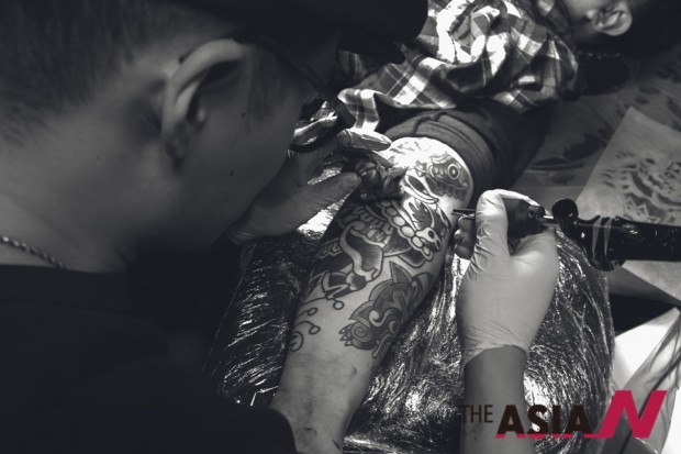 Tattoo artist Kay Lee while tattooing an artwork on a client’s forearm.