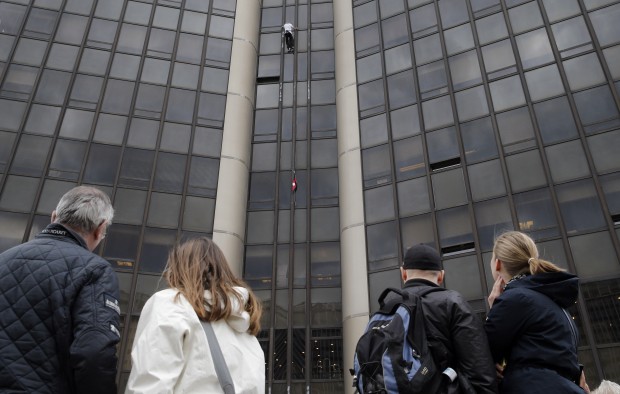 People watch Alain Robert, also known as the French Spiderman, as he climbs the Montparnasse tower a 210-metre (689 ft) office skyscraper located in the Montparnasse area of Paris, France, Tuesday, April 28, 2015. Robert decided to climb in solidarity with the victims of the Saturday's earthquake in Nepal. (AP Photo)