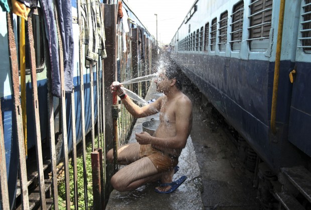 An Indian passenger takes a bath beside rail tracks on a hot summer day at a railway station in Jammu, India, Monday, May 25, 2015. Severe heat wave conditions continue to prevail at several places in northern India with temperatures reaching 48 degrees Celsius (118 degrees Fahrenheit). (AP Photo)