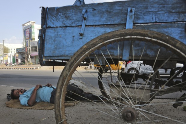 An Indian rickshaw puller rests under the shade of an overhead bridge on a hot summer day in Hyderabad, India, Monday, May 25, 2015. Hundreds of people have died since mid-April in a heat wave sweeping two southeast Indian states, Andhra Pradesh and Telangana, officials said Saturday. (AP Photo)