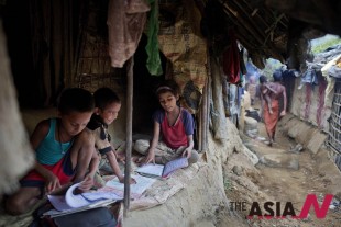 In this Thursday, May 21, 2015 photo, children read books inside their makeshift tent at a camp for Rohingya people in Ukhiya, near Cox's Bazar, a southern coastal district about 296 kilometers (183 miles) south of Dhaka, Bangladesh. As a boat people crisis emerged in Southeast Asia in recent weeks, nearly all the focus has been on the Rohingya: the persecuted Muslim minority fleeing Myanmar. But of the more than 3,000 people who have come ashore this month in Indonesia, Malaysia and Thailand, about half were from Bangladesh, according to the U.N. refugee agency, mainly poor laborers seeking better jobs and a brighter future. (Photo : AP)