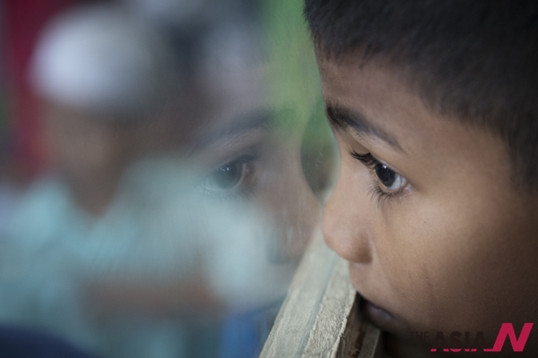 In this May 21, 2015 photo, Sadhussin Mohamad, 6, a Rohingya schoolboy, watches teacher day celebrations outside his classroom  at a Rohingya Education Center in Klang, Malaysia. With more work opportunities than Indonesia and a more Muslim-friendly environment than Thailand, Malaysia has long been the destination of choice for Rohingya Muslims fleeing persecution in Myanmar. 