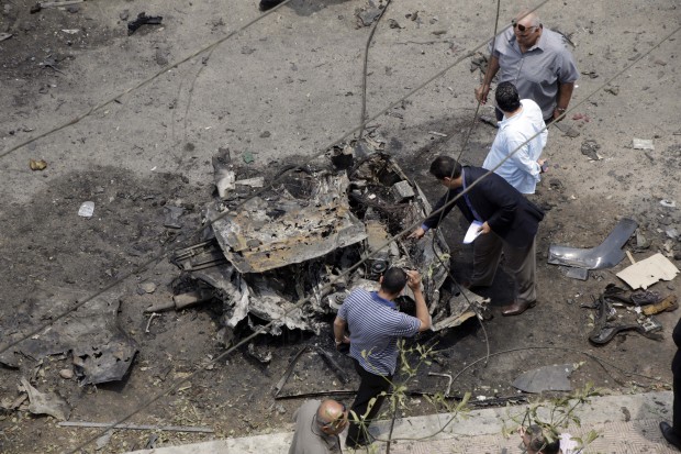 Security personnel inspect damage of a car believed to be the bombed car, after a bomb attack that targeted Egypt's General Prosecutor Hisham Barakat in the Heliopolis district of Cairo, Egypt, Monday, June 29, 2015. An Egyptian militant group, known as Popular Resistance in Giza, has claimed responsibility for the morning bomb attack in Cairo that targeted Barakat, wounding him and several others. (AP Photo)