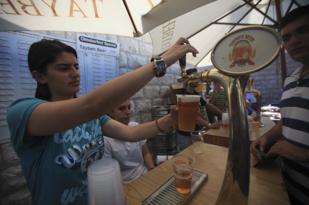 A Palestinian waitress pours beer during the 15th Taybeh festival, in the West Bank town of Taybeh, near Ramallah, Oct. 3, 2010. The annual festival organized in a Christian village located in a Muslim majority area that widely disapproves of drinking and making alcohol. Taybeh beer is considered the first competitor Palestinian beer in the middle east that has been exported to more than 30 countries in the world. (Xinhua/Fadi Arouri) 