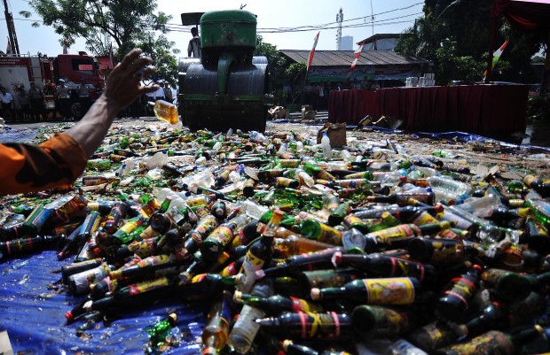 Bottles of confiscated illegal alcohol are destroyed in a pre-Ramadan anti-alcohol campaign at a police station in Jakarta, Indonesia, July 8, 2013. In every Ramadan, the holiest month in Muslim calendar, the government conducts raids at unlicensed liquor stores and destroys the liquor in a pubic display. (Xinhua/Zulkarnain)(xzj)  