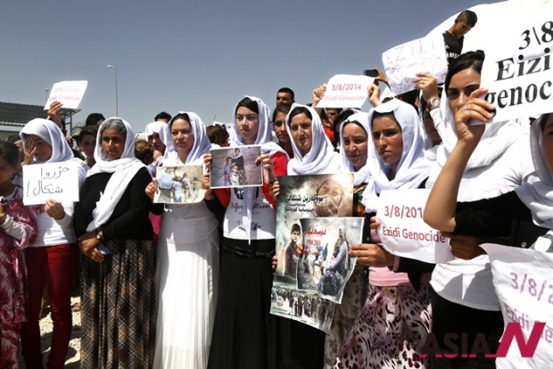 Yazidi Kurdish women hold posters during a protest against the Islamic State group's invasion on Sinjar city one year ago, in Dohuk, northern Iraq, Monday, Aug. 3, 2015. Thousands of Yazidi Kurdish women and girls have been sold into sexual slavery and forced to marry Islamic State militants, according to Human Rights organizations, Yazidi activists and observers. (AP Photo/Seivan M.Salim)