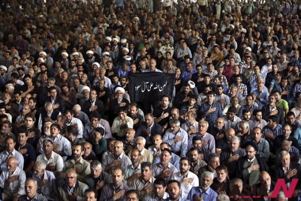 Iranian mourners attend the funeral ceremony of some pilgrims who were killed in a stampede during the hajj pilgrimage in Saudi Arabia last month, as a mourner holds a banner which reads in Arabic, "May Allah Curse Al-Saud," referring to Saudi Arabia's ruling family, at Tehran University, in Tehran, Iran, Sunday, Oct. 4, 2015. Thousands of mourners attended funeral services for the pilgrims. Iran has blamed Saudi authorities for the disaster, which heightened tensions between the two regional rivals. Saudi authorities say 769 pilgrims died in the stampede near Mecca in the worst disaster to strike the annual pilgrimage in a quarter-century. Iran appears to have lost the largest number of pilgrims, with 464 dead. (AP Photo/Vahid Salemi) 