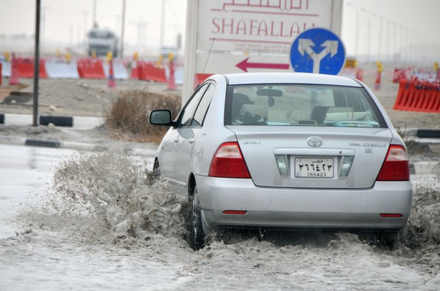 A car drives through a flooded street in Doha, capital of Qatar, Jan. 19, 2011. The continuous rain hit Qatar since monday, causing travel inconvenience for local residents. (Xinhua/Du Jian)