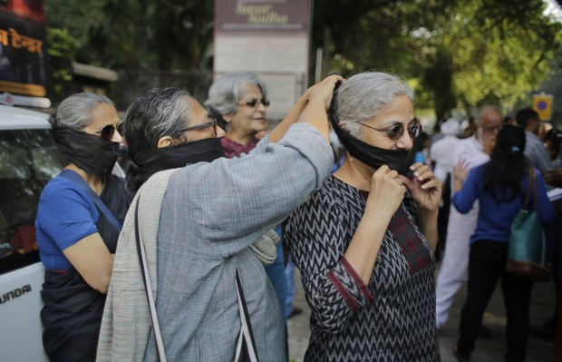 In this Oct. 23, 2015 file photo, an Indian writer assists another with tying a black band around her mouth as a mark of protest before participating in a silent protest march outside Sahitya Akademi, or National Academy of Letters, in New Delhi, India. The chorus of Indian intellectuals protesting religious bigotry and communal violence grows louder by the week with a single message for prime minister Narendra Modi: assure the multicultural nation that the government stands for secularism and diversity. Those protesting are angry and worried by a spate of deadly attacks against atheist thinkers and minorities, and by Modi's relative silence through it all. (AP Photo/Altaf Qadri)