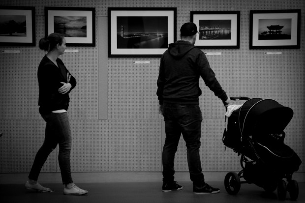 A family observes the photographs at the exhibition.