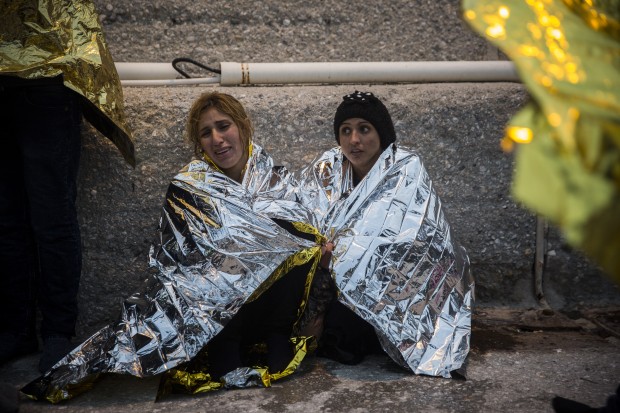 Women wearing thermal blankets react after being rescued, when their boat sank, along with some dozens of other migrants and refugees aboard, on their way from Turkey to the Greek island of Lesbos, at the port town of Petra, Lesbos, Greece, on Wednesday, Dec. 16, 2015. (AP Photo/Santi Palacios)