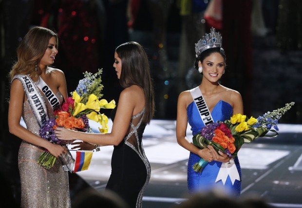 Former Miss Universe Paulina Vega, center, takes away the flowers and sash from Miss Colombia Ariadna Gutierrez, left, before giving it to Miss Philippines Pia Alonzo Wurtzbach, right, at the Miss Universe pageant Sunday, Dec. 20, 2015, in Las Vegas. According to the pageant, a misreading led the announcer to read Miss Colombia Ariadna Gutierrez as the winner before they took it away and gave it to Miss Philippines.(AP Photo/John Locher)