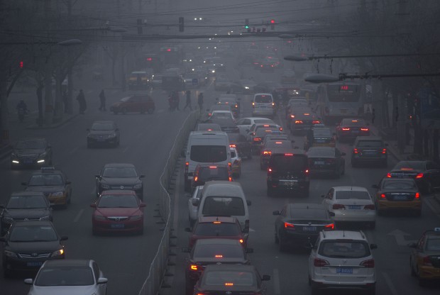 Pedestrians make their way across a busy intersection on a day with severe air pollution in Beijing, Friday, Dec. 25, 2015. Air quality soared to hazardous levels in China's capital on Friday as officials in China's capital issued an orange air pollution alert, the second-highest level alert and just days after the city's second-ever pollution red alert expired. (AP Photo/Mark Schiefelbein)