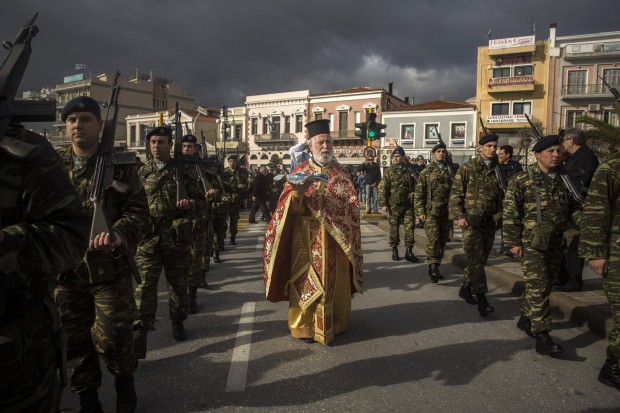 In Greece, an Orthodox priest holds a cross as he is accompanied by a guard of honor during an Epiphany ceremony to bless the water in Mytilene port on the northeastern Greek island of Lesbos. Similar ceremonies to mark Epiphany Day were held across Greece at the sea, rivers, lakes and dams.  (AP Photo/Santi Palacios)