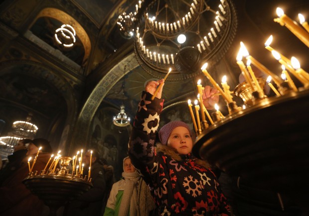 In Ukraine, people light candles in a church to mark the Orthodox Christmas in the St. Volodymyr Cathedral in Kiev. (AP Photo/Sergei Chuzavkov)