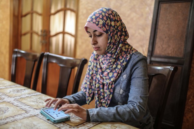 Palestinian college student Israa Al-ashqar ,23, works on an application on her mobile phone. (Xinhua/Wissam Nassar)