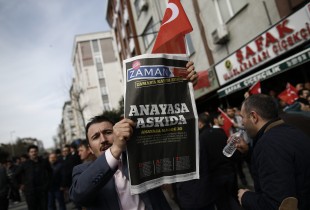 A man holds Saturday copy of the newspaper with its headline reads " the constitution suspended "as people gathered in support outside the headquarters of Zaman newspaper in Istanbul, Sunday, March 6, 2016. The European Union is facing increasing pressure to speak out against the erosion of media freedom in Turkey following the takeover of the country's largest-circulation newspaper, but few expect it to take a bold stance toward Ankara while trying to assure its help in dealing with the migration crisis. Police used tear gas and water cannons for a second day running on Saturday to disperse hundreds of protesters who gathered outside the headquarters of Zaman newspaper  now surrounded by police fences. (AP Photo/Emrah Gurel)