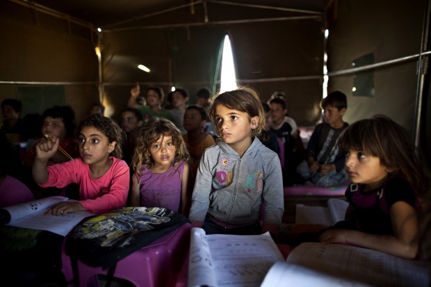 Syrian refugee children attend a class at a makeshift school set up in a tent at an informal tented settlement near the Syrian border on the outskirts of Mafraq, Jordan. The U.N. agency for children says more than 80 percent of Syria's children have been harmed by the five-year-old conflict, including growing numbers forced to work, join armed groups or marry young because of widening poverty. (AP Photo/Muhammed Muheisen, File)
