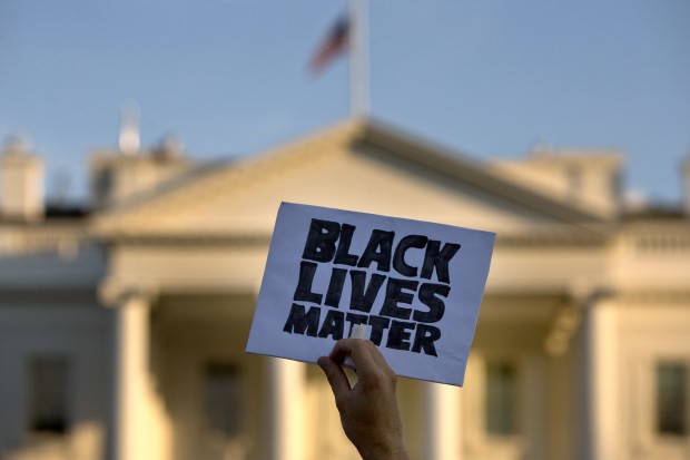 In this July 8, 2016, photo, a man holds up a sign saying "black lives matter" during a protest of shootings by police, in Washington by the White House. When it comes to picking a new president, young people in America are united in saying education is what matters most. But there's a wide split in what else will drive their votes. The poll showed major support for the Black Lives Matter movement among African-Americans polled — 84 percent. Support for Black Lives Matter polled at 68 percent for Asian-Americans, 53 percent for Hispanics and 41 percent for whites. (AP Photo/Jacquelyn Martin)