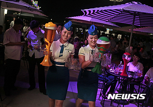 Waitresses carry pitchers of beer during Taedonggang Beer Festival in Pyongyang, North Korea, Sunday, Aug. 21, 2016. The festival, the first of its kind in the country, was held as a promotional event for the locally brewed beer. (AP Photo/Dita Alangkara) 