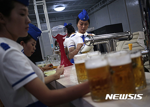 A beer server fills up glasses of draft beer at a beer festival held along the Taedong River on Friday, Aug. 12, 2016 in Pyongyang, North Korea. (AP Photo/Kim Kwang Hyon) 