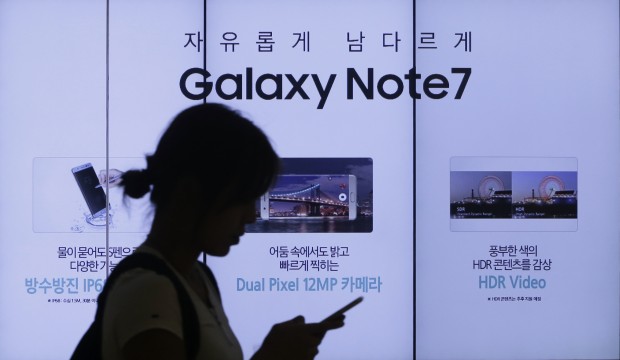 Sept. 2, 2016, file photo, a woman walks by an advertisement of the Samsung Electronics Galaxy Note 7 smartphone at the company's showroom in Seoul, South Korea. The Federal Aviation Administration said Thursday night, Sept. 8, 2016, that because of recent fire reports involving the Galaxy Note 7 smartphone, passengers shouldn’t use or charge one or stow one in checked baggage. The three biggest U.S. airlines: American, Delta and United, said Friday that they were studying the FAA warning but it was unclear how they would make sure that passengers keep the Samsung devices powered off. (AP Photo/Ahn Young-joon, File)