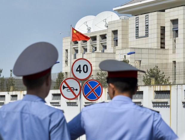 Kyrgyz police officers look at the Chinese Embassy in Bishkek, Kyrgyzstan, Tuesday, Aug. 30, 2016. A suspected suicide bomber on Tuesday crashed a car through the entrance of the Chinese Embassy in the Kyrgyzstan capital of Bishkek, detonating a bomb that killed the attacker and wounded embassy employees. (AP Photo/ Vladimir Voronin)