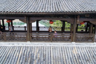 CHONGQING, Sept. 30, 2016 -- Aerial photo taken on Sept. 29, 2016 shows tourists visiting the covered bridge across the Apeng River in southwest China's Chongqing. Those previous wooden buildings covering the bridge were destroyed by fire in 2013, and the bridge reopened one year later after reconstruction. (Xinhua/Liu Chan)