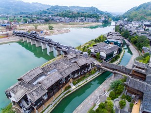 CHONGQING, Sept. 30, 2016 -- Aerial photo taken on Sept. 29, 2016 shows tourists visiting the covered bridge across the Apeng River in southwest China's Chongqing. Those previous wooden buildings covering the bridge were destroyed by fire in 2013, and the bridge reopened one year later after reconstruction. (Xinhua/Liu Chan)