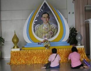 Thais pray in front of a portrait of Thai King Bhumibol Adulyadej in Bangkok, Thailand, Tuesday, Oct. 11, 2016.