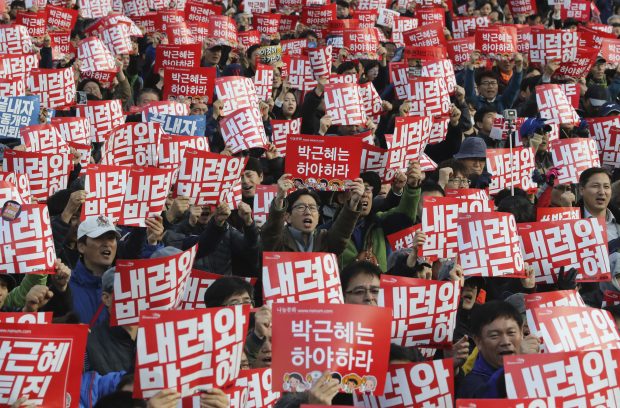 South Korean protesters hold up cards during a rally calling for South Korean President Park Geun-hye to step down in Seoul, South Korea, Saturday, Nov. 12, 2016. Tens, and possibly hundreds, of thousands of South Koreans marched in Seoul on Saturday demanding the ouster of President Park Geun-hye in one of the biggest protests in the country since its democratization about 30 years ago. The letters read " Step down, Park Geun-hye." (AP Photo/Lee Jin-man)