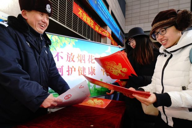 A campaign to advocate no use of fireworks for sake of less air pollution was held in Dongcheng District, Beijing in January. The picture taken shows a public security officer introducing the significance of less fireworks. (Photo by He Yong from People's Daily)