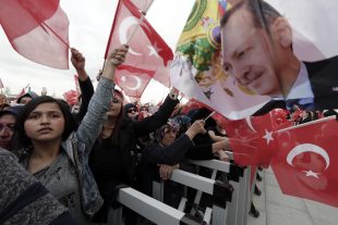 Supporters wave flags as Turkey's President Recep Tayyip Erdogan delivers a speech during a rally of supporters a day after the referendum, at his palace, in Ankara, Turkey, Monday, April 17, 2017. Turkey's main opposition party urged the country's electoral board Monday to cancel the results of a landmark referendum that granted sweeping new powers to Erdogan, citing what it called substantial voting irregularities. (AP Photo/Burhan Ozbilici)