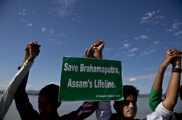 In this Monday, Dec.11, 2017 photo, students from India's northeastern Assam state hold hands by the Brahmaputra river during a protest against the contamination of the river in Gauhati, India. Officials in India's northeast are complaining that Chinese construction activity on the upper reaches of one of the largest rivers that flows into India are likely turning the waters downstream turbid and unfit for human consumption. (AP Photo/Anupam Nath)