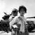 With her brother on her back a war weary Korean girl tiredly trudges by a stalled M-26 tank, at Haengju, Korea.  June 9, 1951.  Maj. R.V. Spencer, UAF. (Navy)
NARA FILE #:  080-G-429691
WAR & CONFLICT BOOK #:  1485