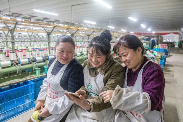 Workers search for topics of their concerns in the government work report at a textile factory in a high-tech development zone of Hai’an, east China’s Jiangsu province. (Photo by People’s Daily Online)