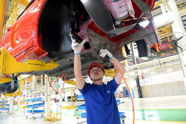 A worker is working on the installation in an electric vehicle production line in RuGao, Nantong, Jiangsu Province, China