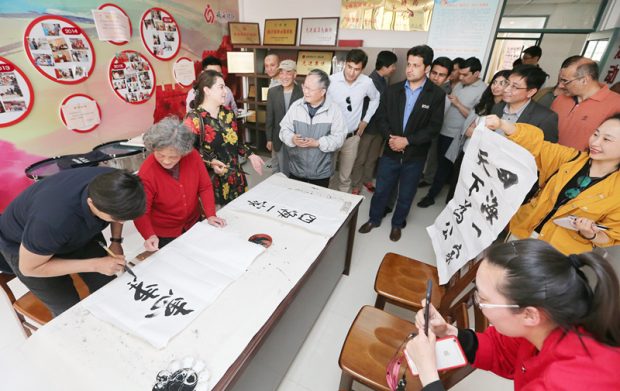 A member from a BRI delegation learns Chinese calligraphy at a Chinese social community, May 9, 2019. (Photo/People’s Daily Online)