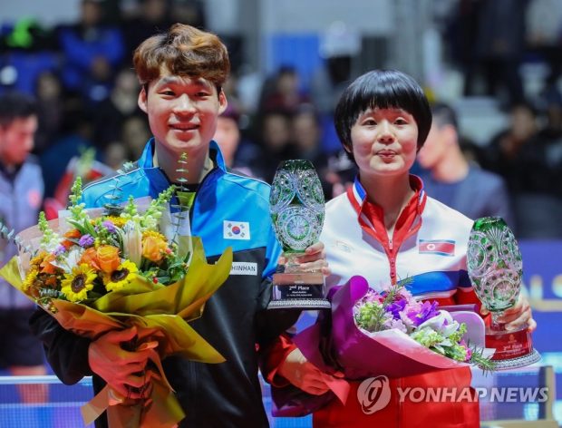 In this file photo from Dec. 15, 2018, Jang Woo-jin of South Korea (L) and Cha Hyo-sim of North Korea hold up their second-place trophies in the mixed doubles during the awards ceremony at the International Table Tennis Federation World Tour Grand Finals at Namdong Gymnasium in Incheon, 40 kilometers west of Seoul. (Yonhap)